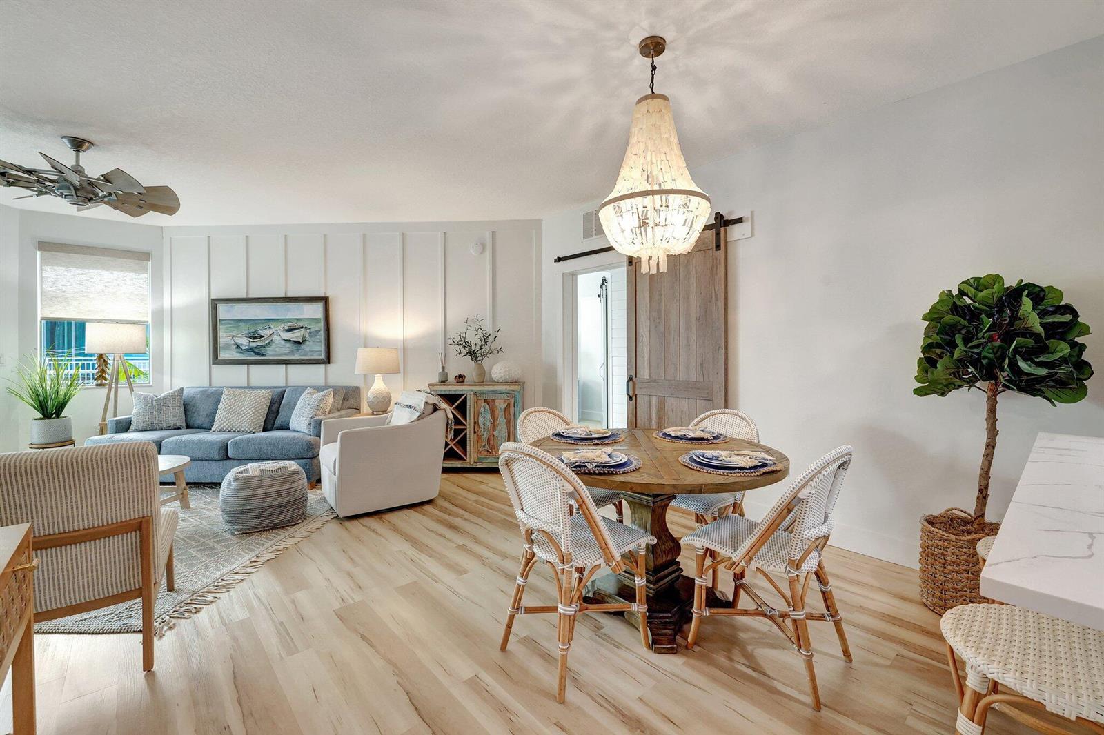 A bright living and dining area features light wood floors, a chandelier, and coastal decor — 875 NW Flagler Avenue # 404, Stuart FL 34994, STUART, FL