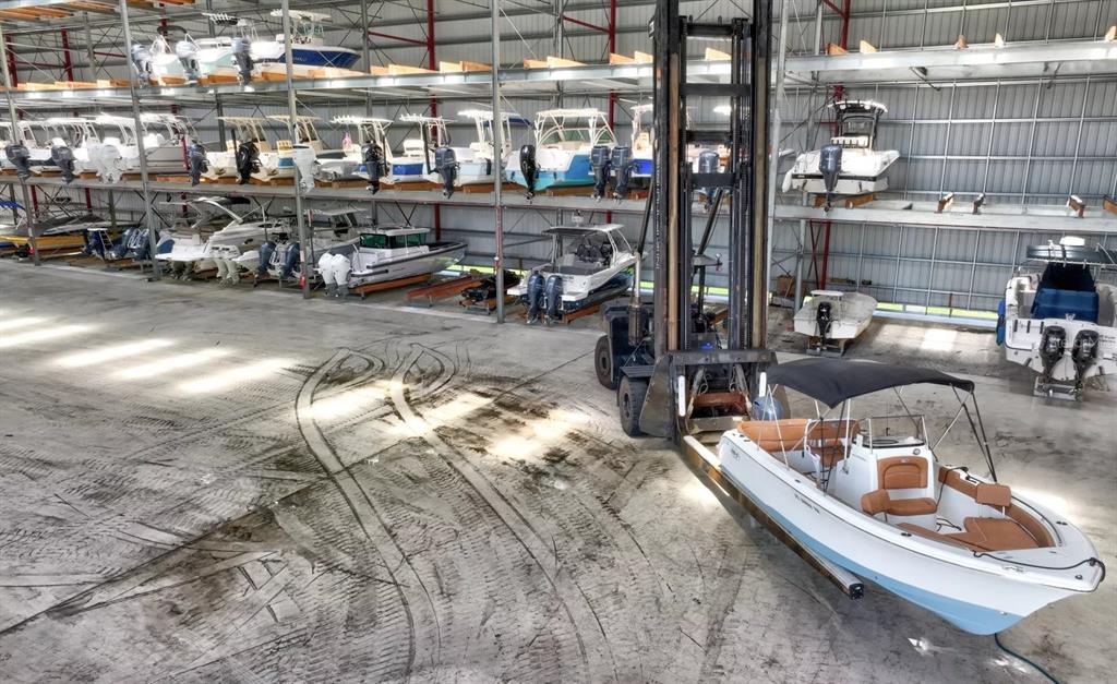 A large indoor boat storage facility features a forklift moving a boat on the floor — 36 RIO VISTA DRIVE, PALM COAST, FL