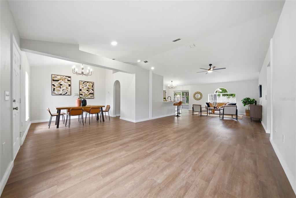 An open-concept living and dining area features light wood-look flooring and white walls — 1223 GATEWOOD AVENUE, SPRING HILL, FL
