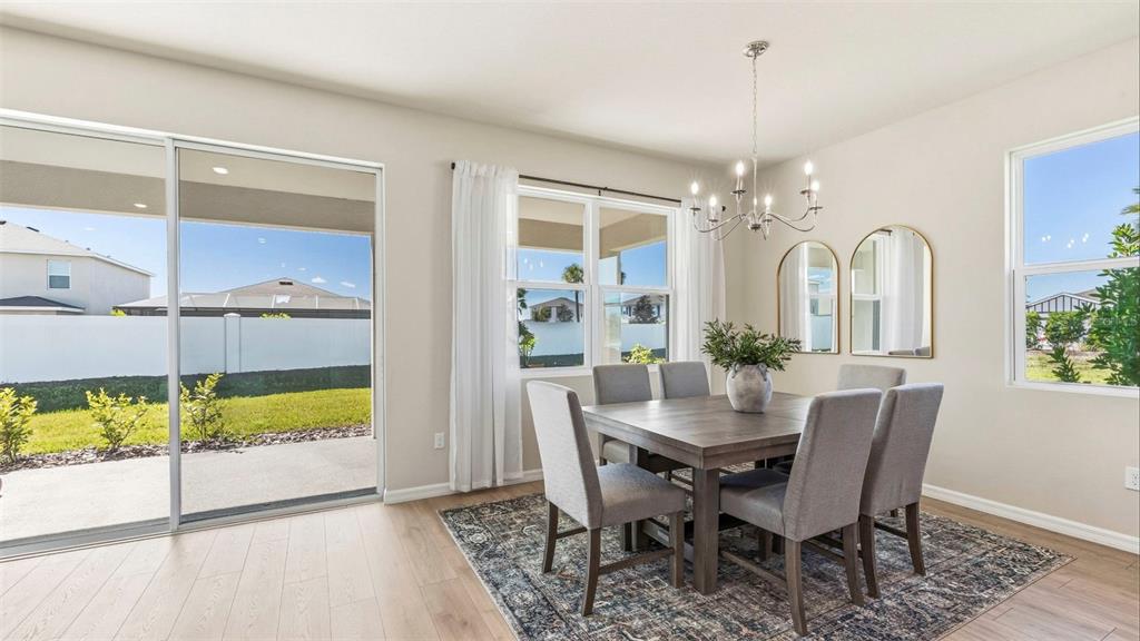 A dining room with a wooden table, six chairs, a chandelier, and a sliding door — 1513 LOVE GRASS TERRACE, PARRISH, FL