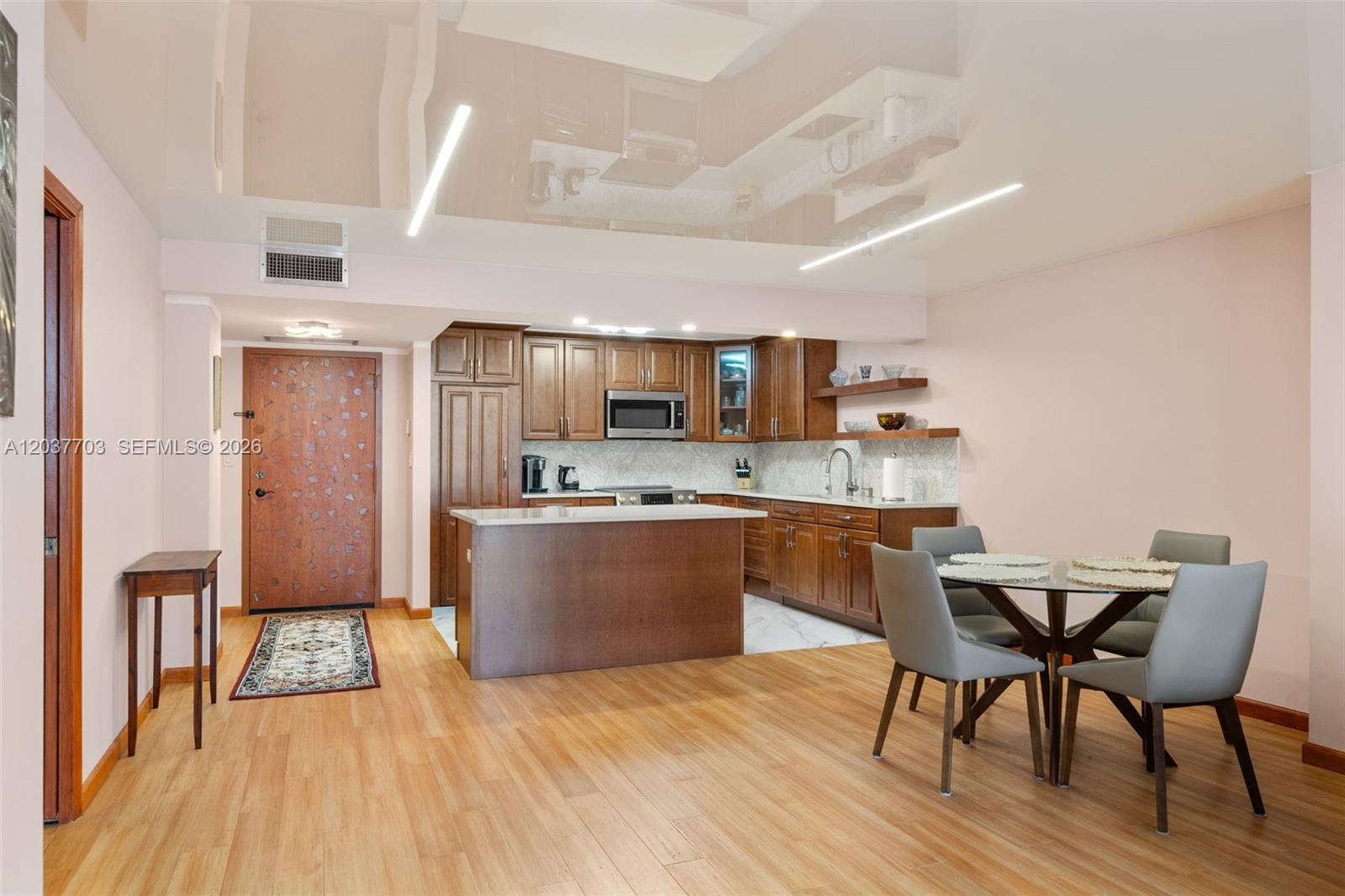 This kitchen and dining area features dark wood cabinetry, a central island, and light flooring — 1865 S Ocean Dr # 16B, Hallandale Beach FL 33009, HALLANDALE BEACH, FL
