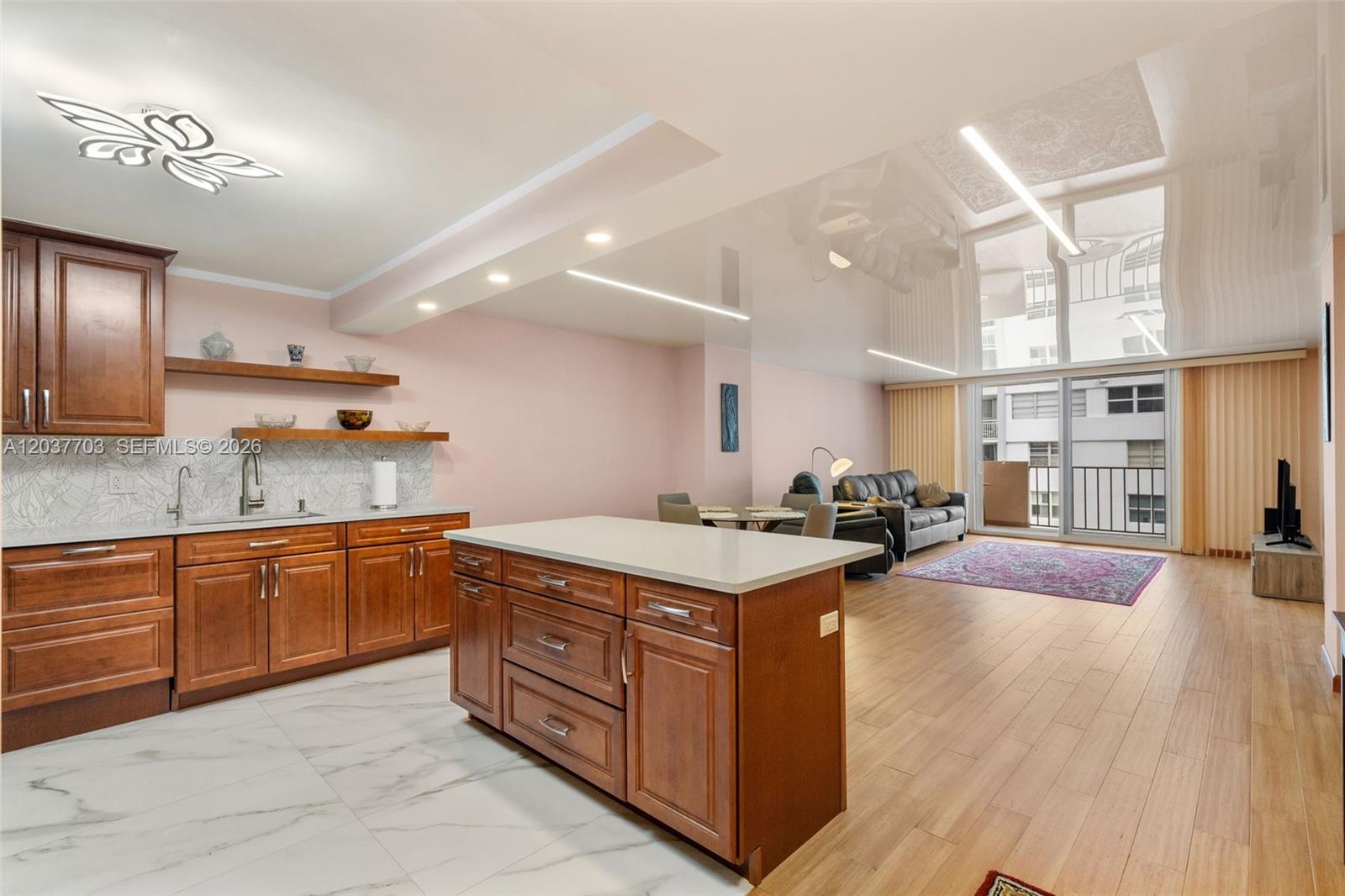 An open-concept kitchen with wood cabinets and a white island overlooks a living area — 1865 S Ocean Dr # 16B, Hallandale Beach FL 33009, HALLANDALE BEACH, FL