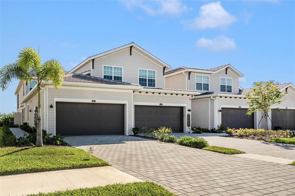 A view of the exterior of two attached suburban houses with paved driveways and garages — 12685 RADIANCE COURT UNIT 101, VENICE, FL