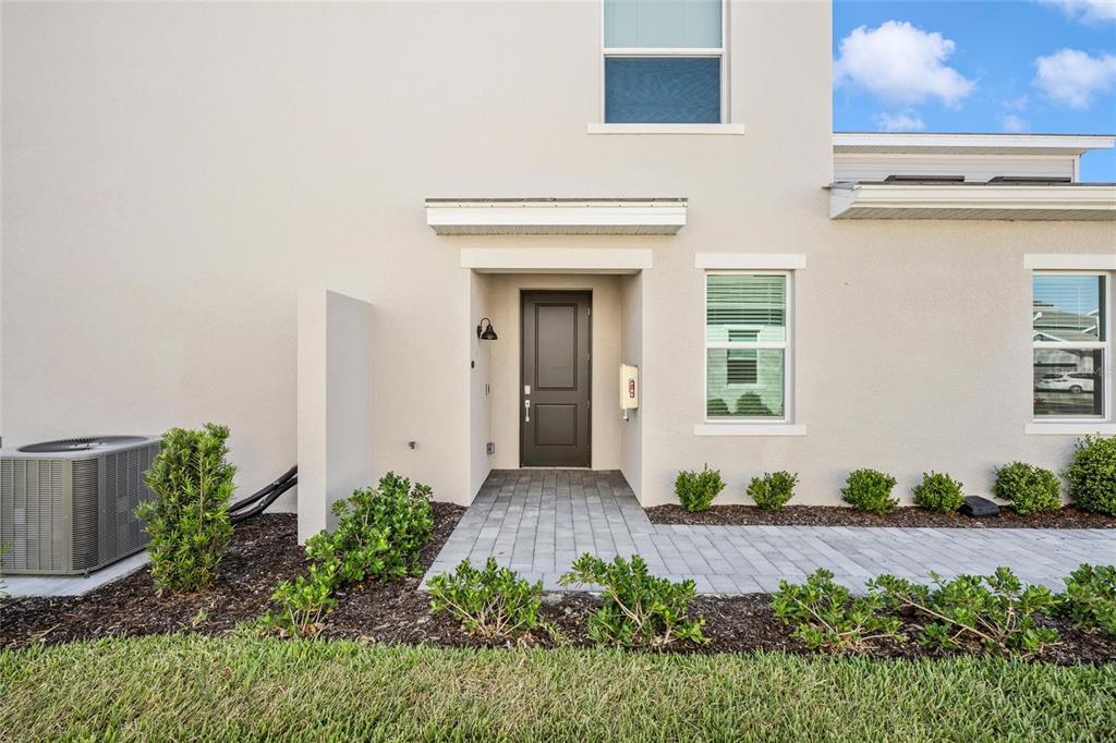 The exterior of a beige house features a dark front door and a paved walkway — 12685 RADIANCE COURT UNIT 101, VENICE, FL