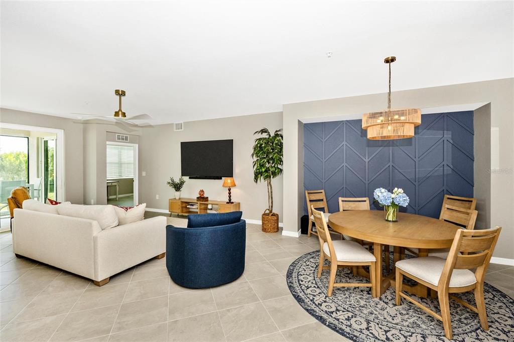 A living and dining area features a blue accent wall, round table, and neutral furniture — 12685 RADIANCE COURT UNIT 101, VENICE, FL