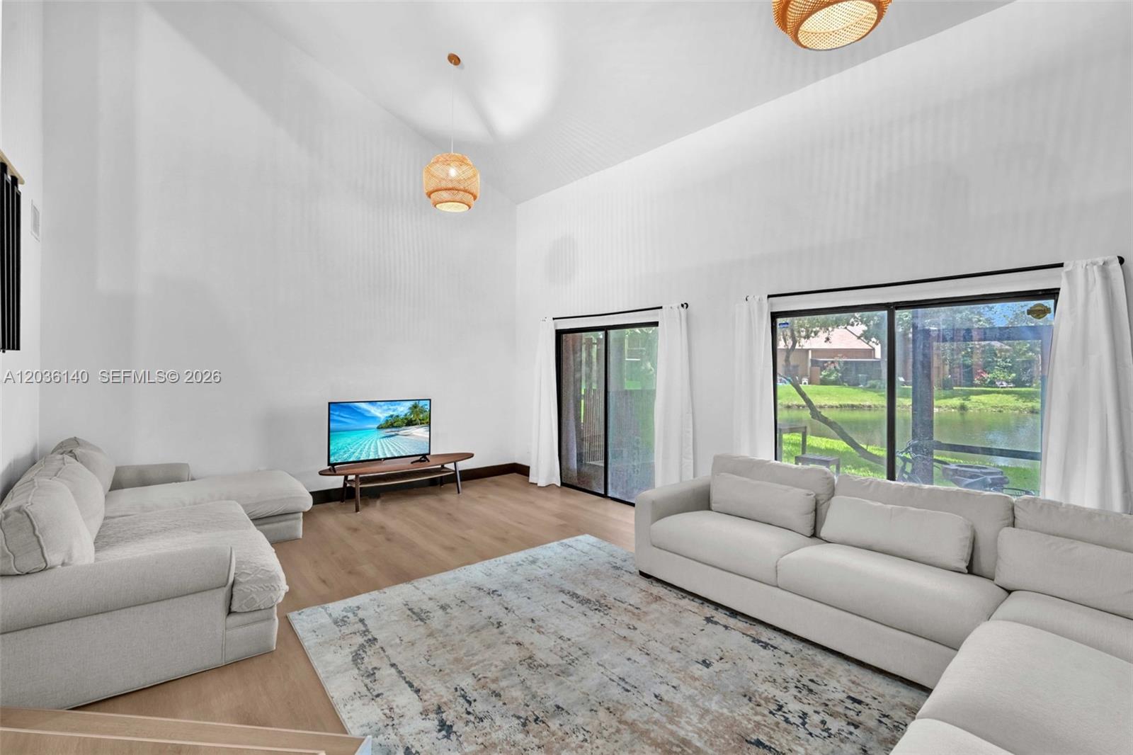 A living room features high ceilings, two light-colored sofas, a rug, and sliding glass doors — 4171 SW 85th Ave, Davie FL 33328, DAVIE, FL