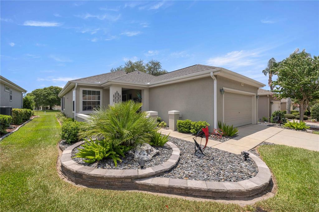 A single-story house with a beige stucco exterior, a two-car garage, and a landscaped front yard — 13260 SE 92ND COURT ROAD, SUMMERFIELD, FL