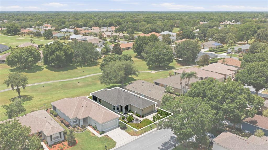 An aerial view shows a single-story house with a gray roof bordering a golf course — 13260 SE 92ND COURT ROAD, SUMMERFIELD, FL