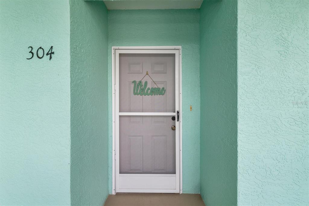 A light green exterior wall features a white front door with a screen door — 19385 WATER OAK DRIVE UNIT 304, PORT CHARLOTTE, FL