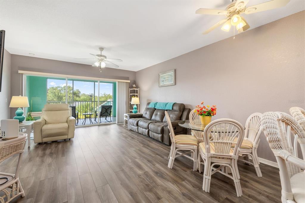 A living and dining area with wood-look flooring, a gray sofa, and a glass dining table — 19385 WATER OAK DRIVE UNIT 304, PORT CHARLOTTE, FL