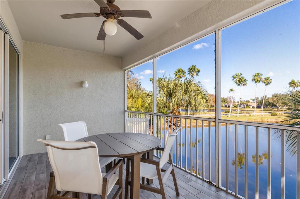 A screened-in balcony features a round table, chairs, a ceiling fan, and a lake view — 3322 GRAND VISTA COURT UNIT 203, PORT CHARLOTTE, FL