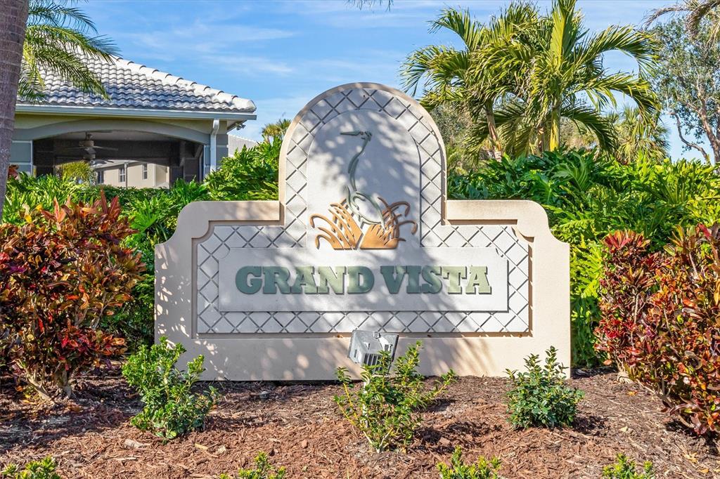 A beige monument sign with a heron emblem reads Grand Vista in a landscaped garden — 3322 GRAND VISTA COURT UNIT 203, PORT CHARLOTTE, FL