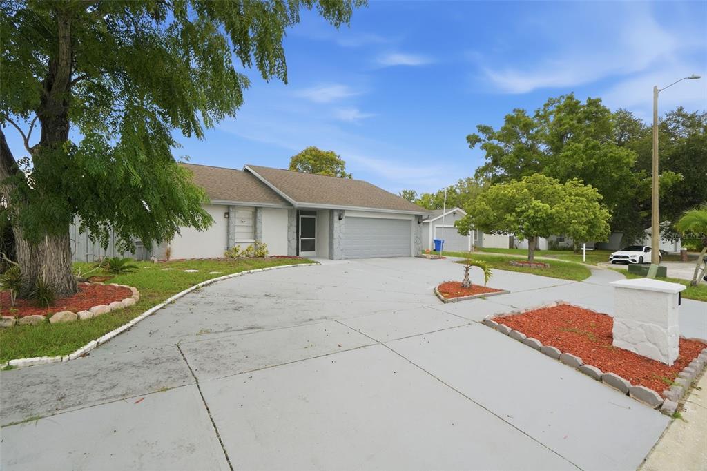 A single-story house with a gray garage, a large concrete driveway, and landscaped front beds — 11320 PARTRIDGE DRIVE, TAMPA, FL