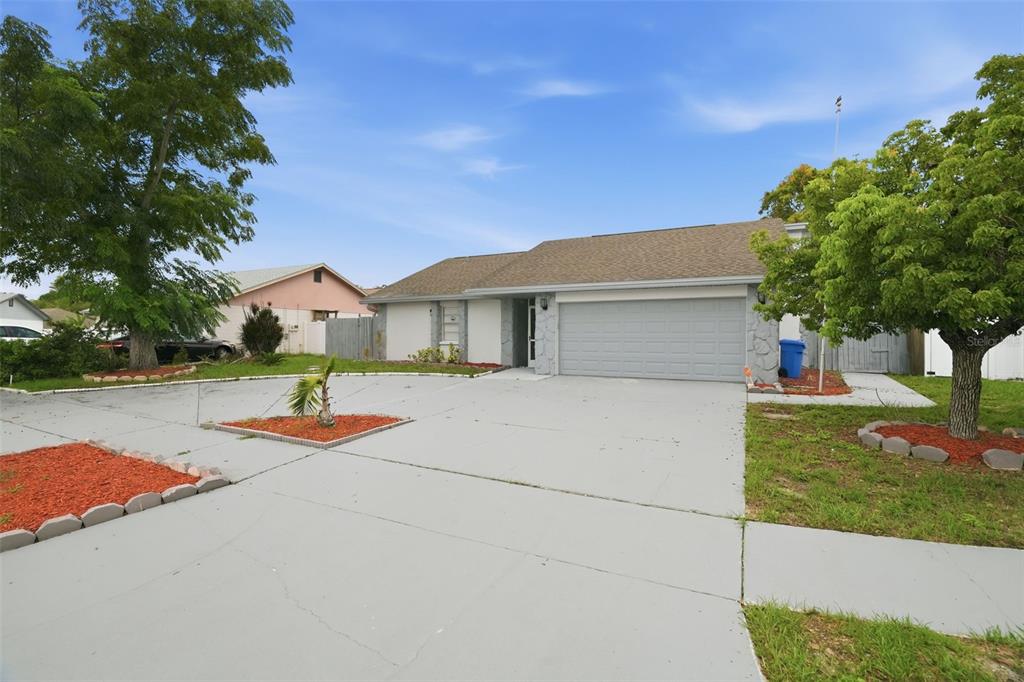A single-story house with a gray garage, stone accents, and a large concrete driveway — 11320 PARTRIDGE DRIVE, TAMPA, FL