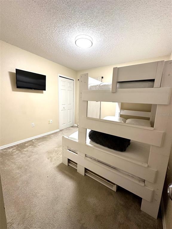 A bedroom features a white bunk bed, beige carpeted flooring, and a wall-mounted television — 307 FOX LOOP, DAVENPORT, FL
