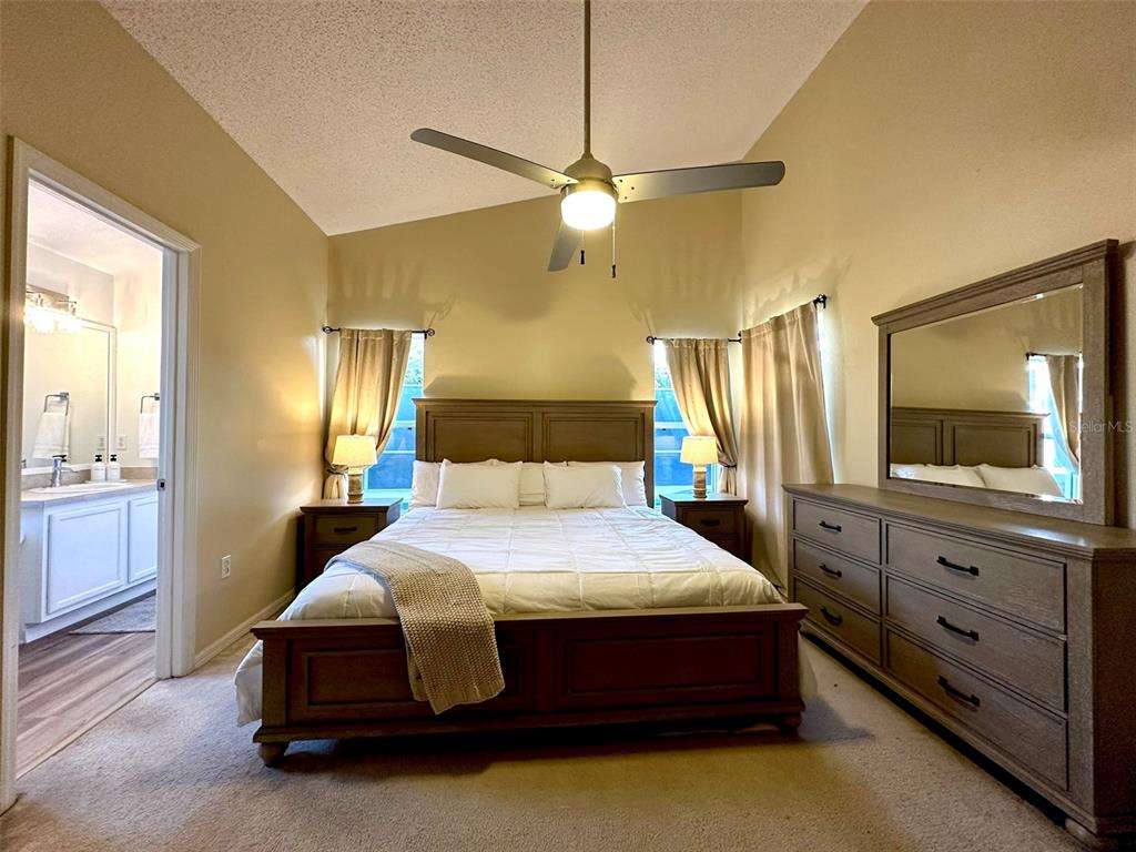 A bedroom features a wooden bed frame, matching dresser with mirror, and an attached bathroom — 307 FOX LOOP, DAVENPORT, FL