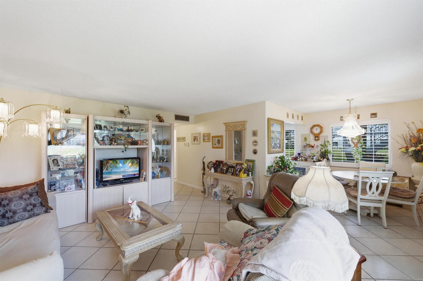 A living room with tile flooring, a large entertainment center, and a dining area — 406 Saxony I, Delray Beach FL 33446, DELRAY BEACH, FL
