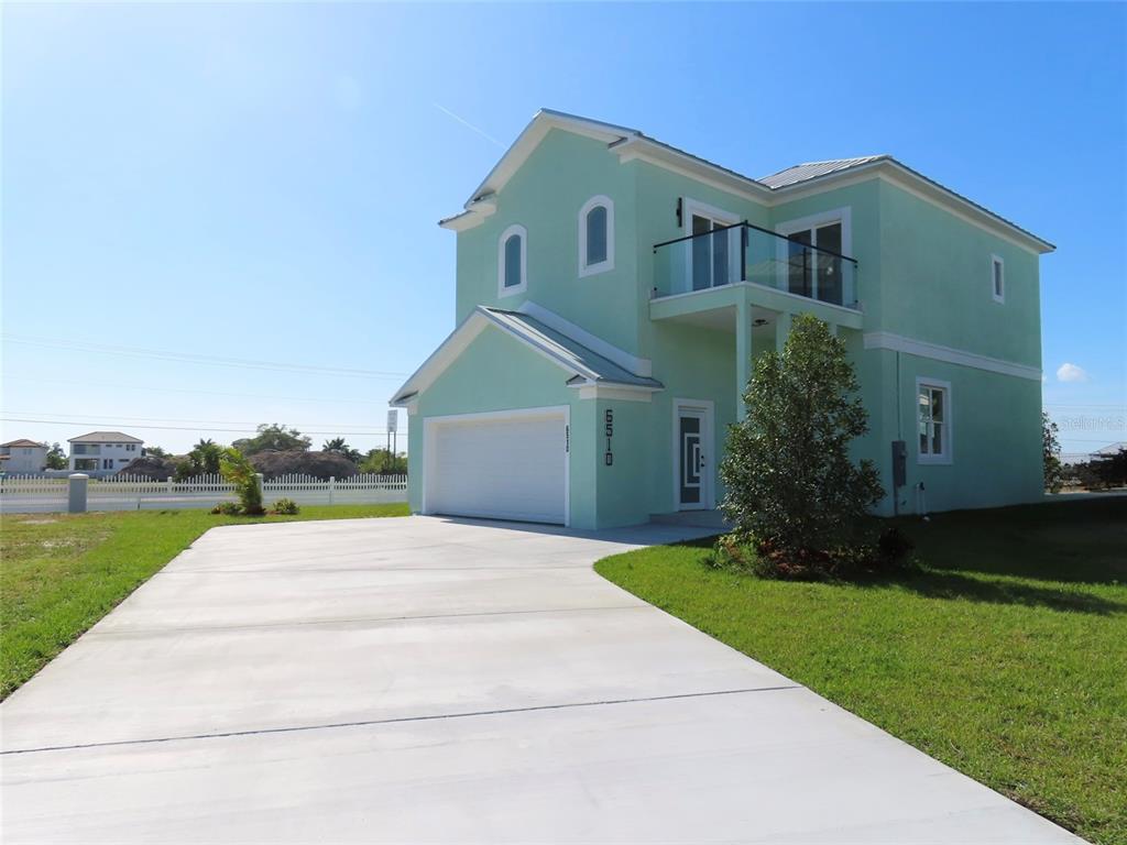 A two-story, light green house with a garage and a second-floor balcony — 6510 SIMONE SHORES CIR, APOLLO BEACH, FL