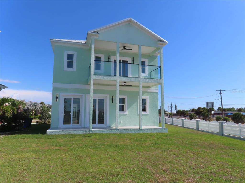 A two-story light green house features a covered porch and a second-floor balcony — 6510 SIMONE SHORES CIR, APOLLO BEACH, FL