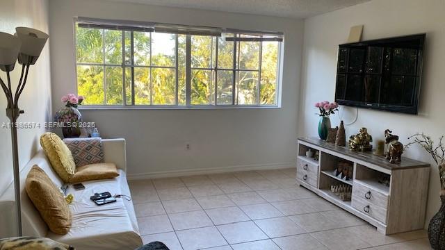 A living room features a white sofa, a television, and a media console on tile floors — 6195 NW 186th St # 309, Hialeah FL 33015, HIALEAH, FL