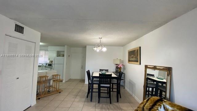 A dining area with a table and chairs sits adjacent to a kitchen with tile floors — 6195 NW 186th St # 309, Hialeah FL 33015, HIALEAH, FL