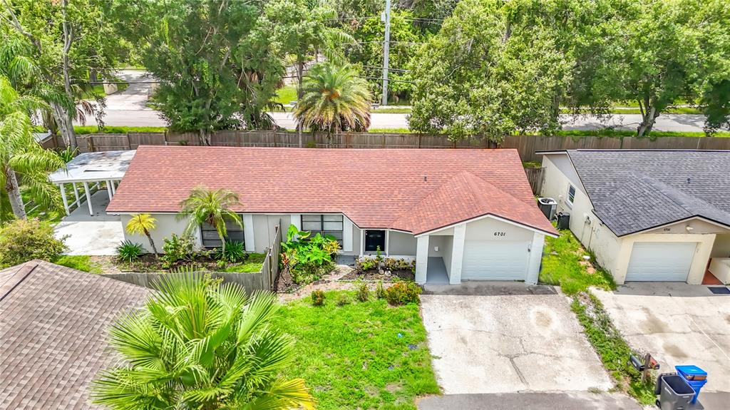 An aerial view shows a single-story house with a reddish-brown roof and a concrete driveway — 6701 VILLAGE GROVE COURT, TAMPA, FL