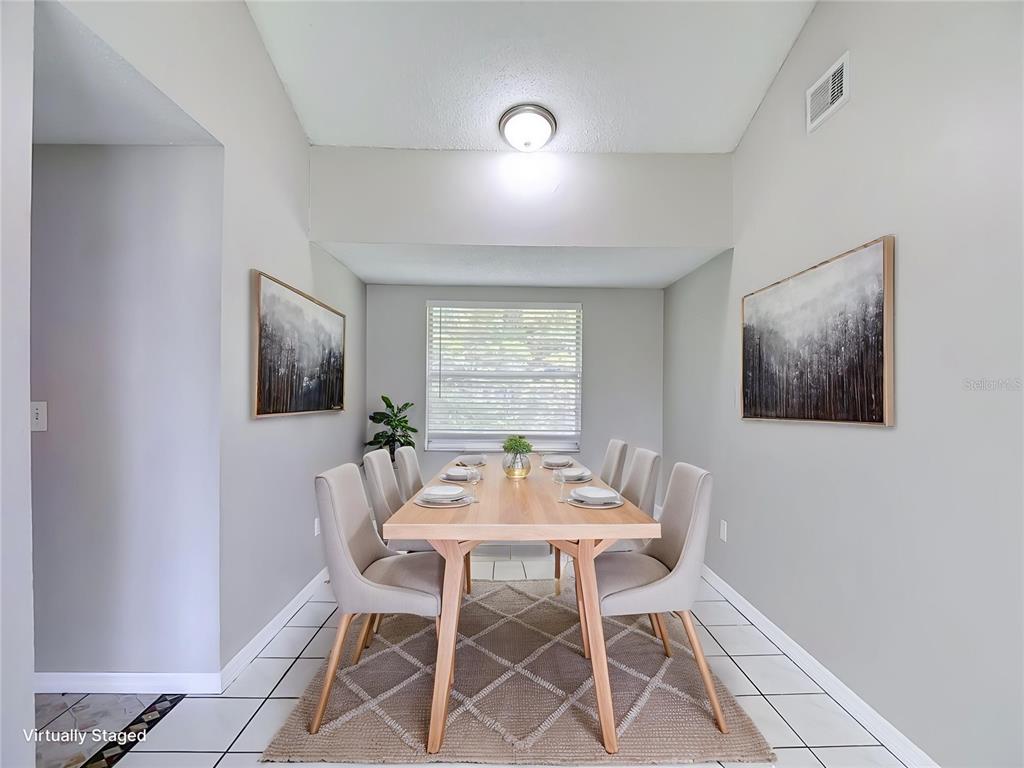 A dining room with a wooden table, six chairs, a rug, and two framed wall paintings — 6701 VILLAGE GROVE COURT, TAMPA, FL
