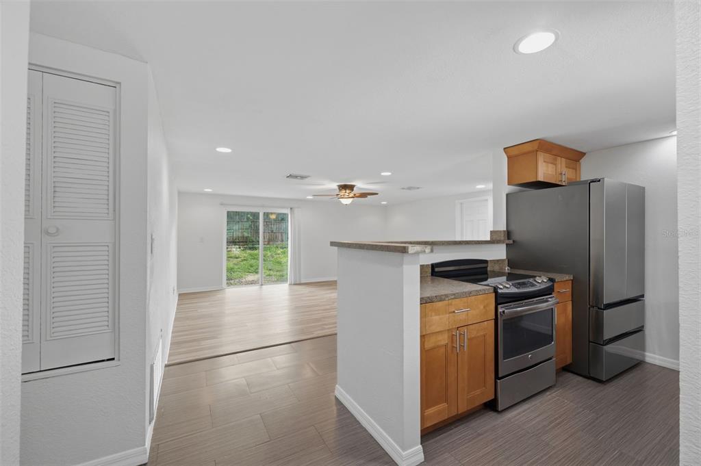 A kitchen with wood cabinets and stainless steel appliances opens to a living area — 2804 APPLEWOOD DRIVE, CLEARWATER, FL