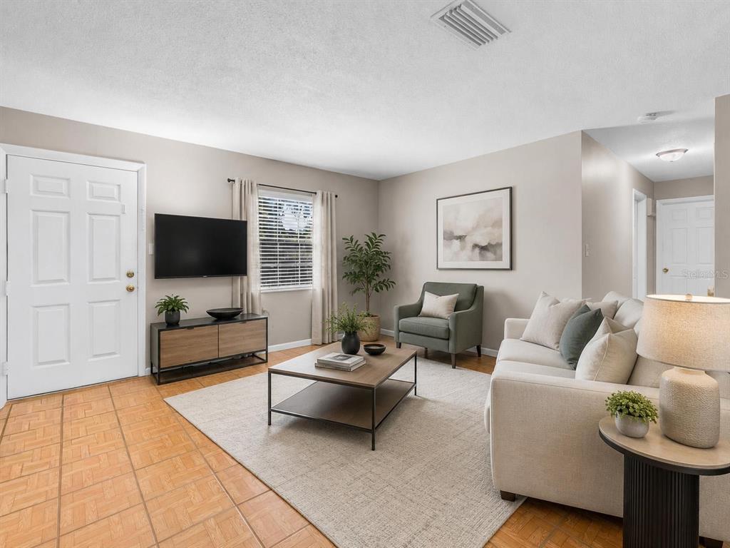 A living room features a beige sofa, a coffee table, and a wall-mounted television — 2510 DRIFTWOOD DRIVE, FERN PARK, FL