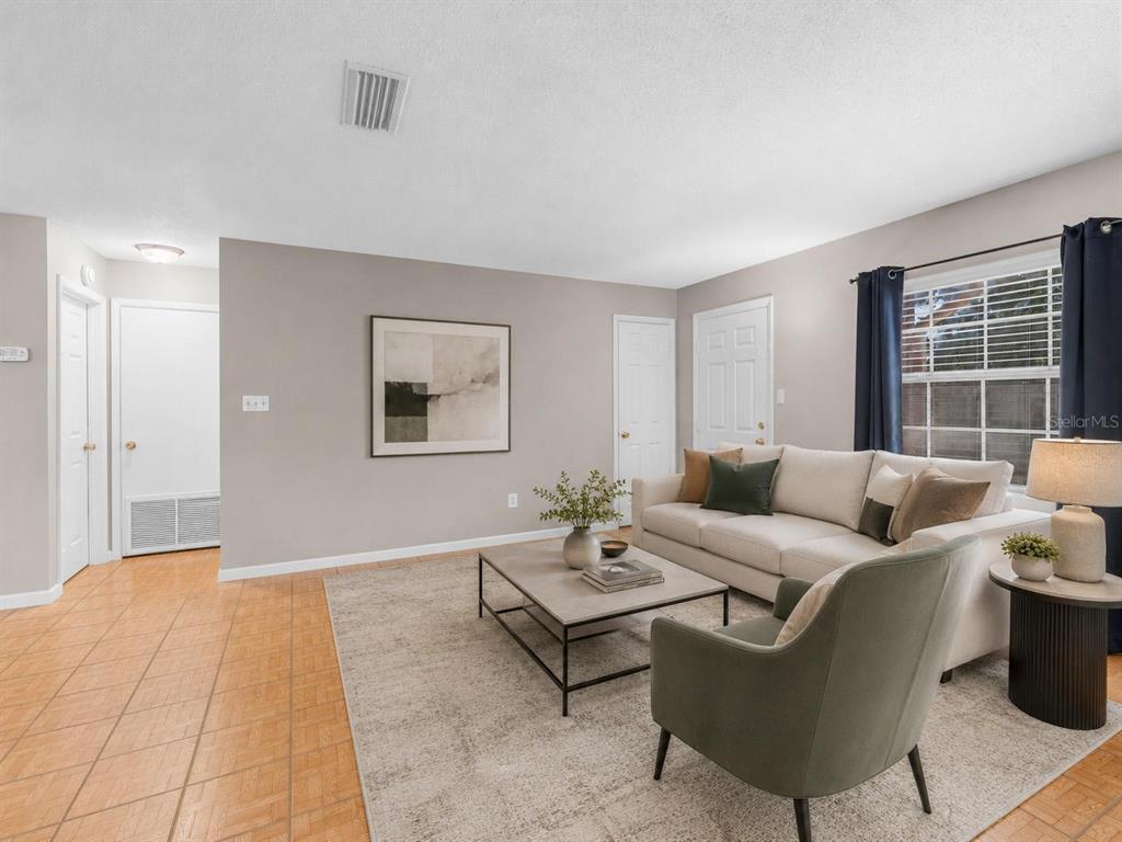 A living room features light gray walls, tile flooring, a beige sofa, and an armchair — 2510 DRIFTWOOD DRIVE, FERN PARK, FL