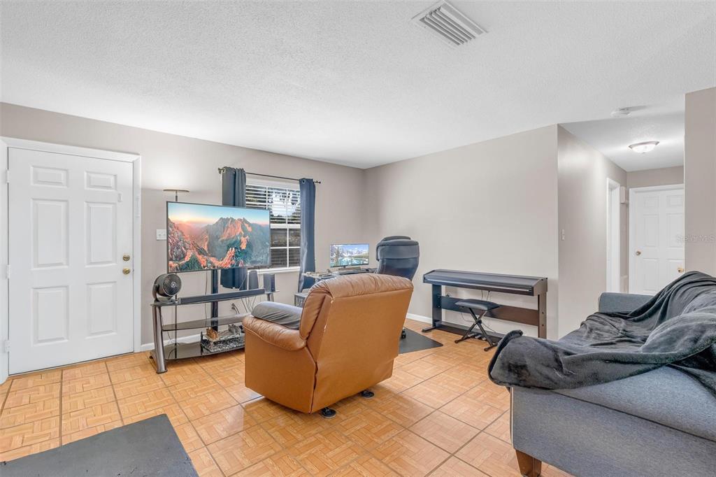A living room features tile flooring, a television on a stand, a recliner, and a keyboard — 2510 DRIFTWOOD DRIVE, FERN PARK, FL