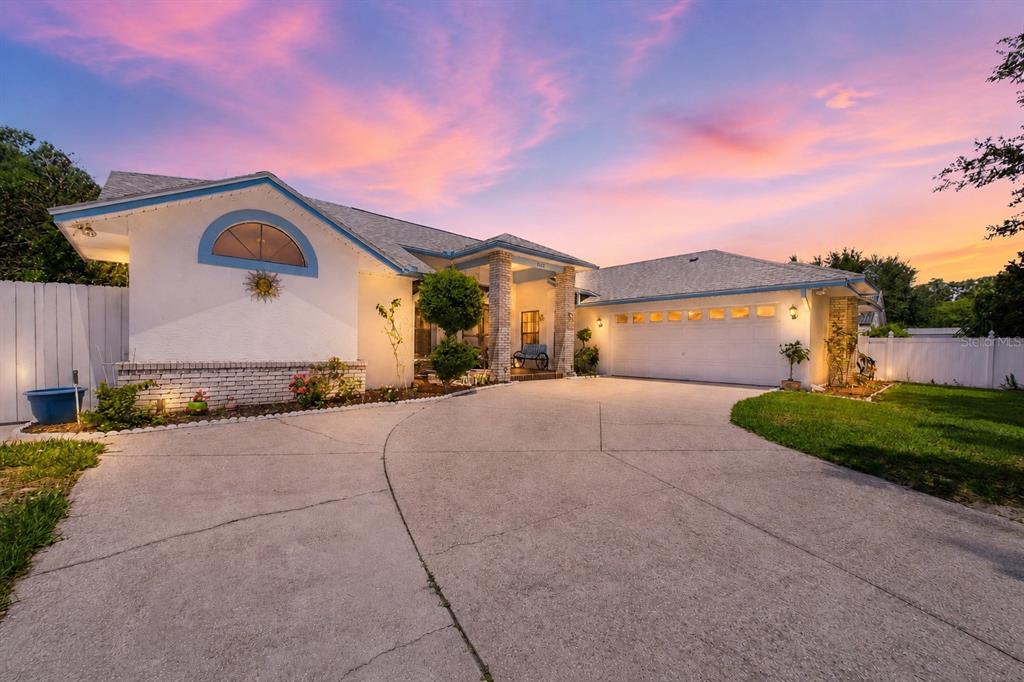 A single-story house with a white stucco facade, brick accents, and a large concrete driveway — 4386 WYNDCLIFF CIRCLE, ORLANDO, FL