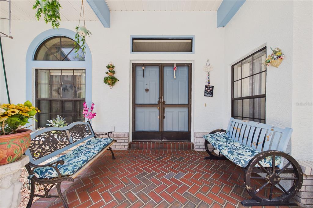 A covered front porch features a brick floor, two benches, and light blue double doors — 4386 WYNDCLIFF CIRCLE, ORLANDO, FL