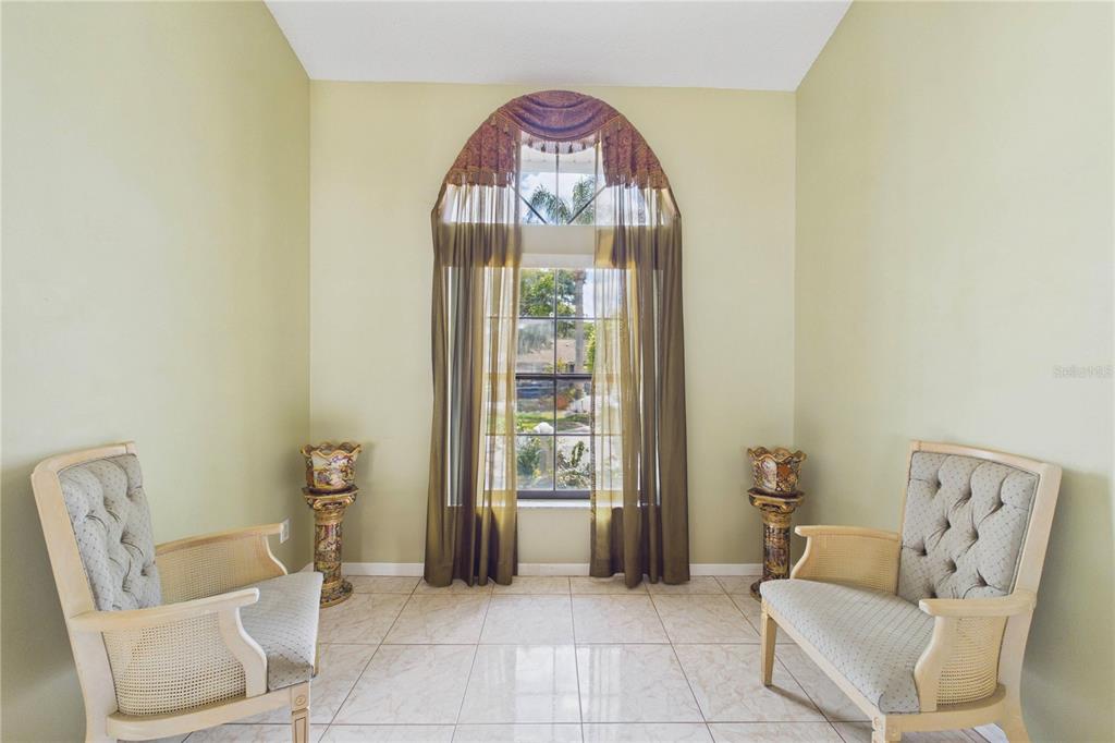 A room with light green walls, tile flooring, two chairs, and a large arched window — 4386 WYNDCLIFF CIRCLE, ORLANDO, FL