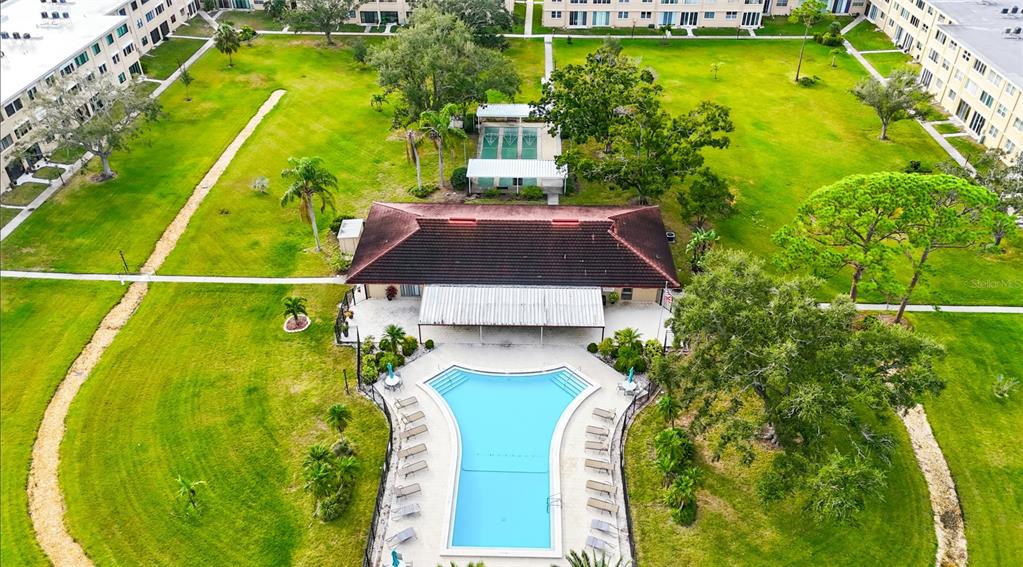 An aerial view shows a community clubhouse with a swimming pool and tennis courts — 5095 BAY STREET NE UNIT 210, ST PETERSBURG, FL