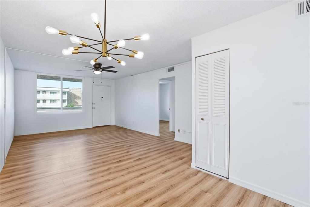An empty room with light wood-look flooring, white walls, a ceiling fan, and a chandelier — 5095 BAY STREET NE UNIT 210, ST PETERSBURG, FL