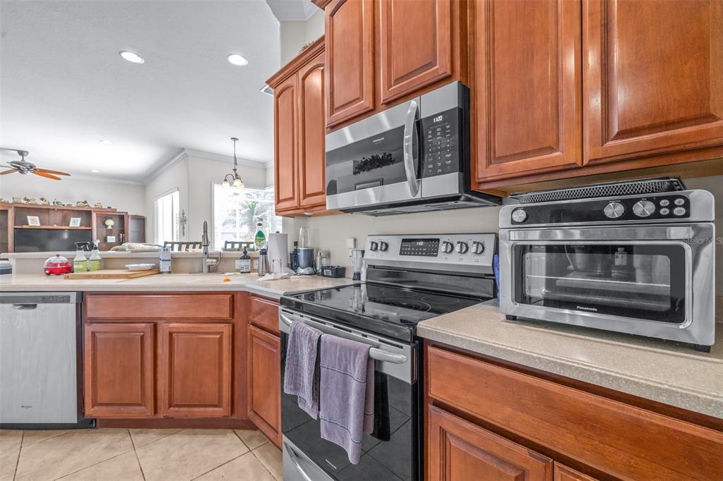 A kitchen features wood cabinets, stainless steel appliances, and a countertop with a toaster oven — 6798 HARTSWORTH DRIVE, LAKELAND, FL