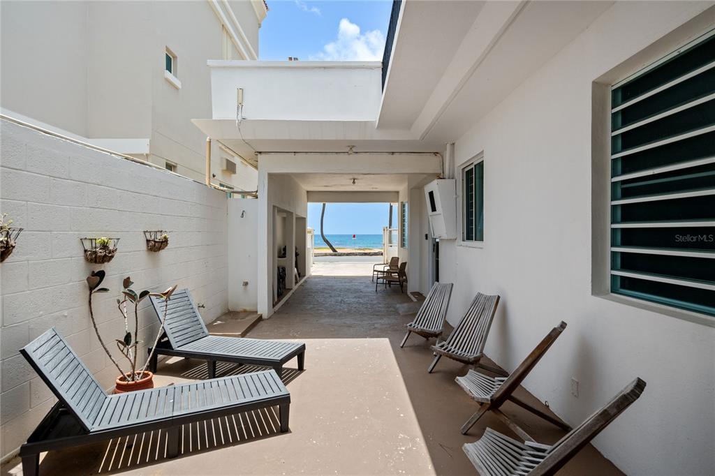A covered patio with lounge chairs leads to an open view of the ocean — Luquillo BEACH UNIT A-25, LUQUILLO, PR