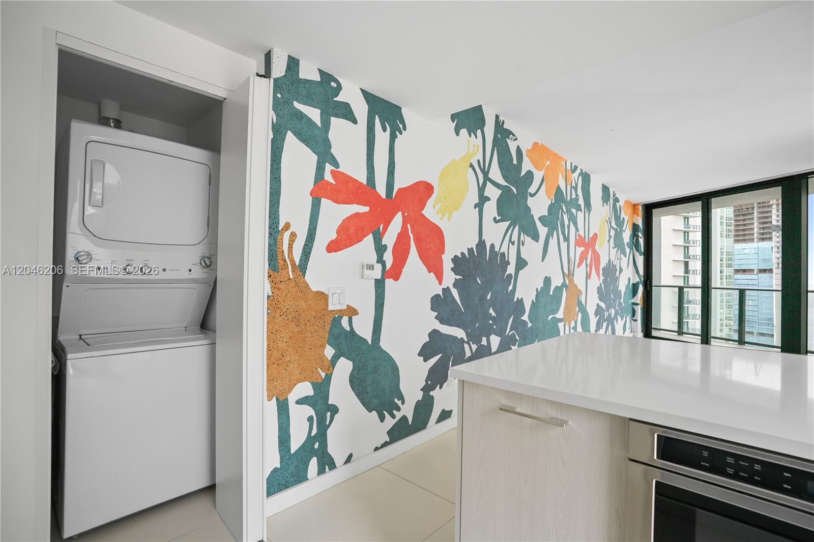 A kitchen area features a stacked washer-dryer unit and a wall with floral wallpaper — 501 NE 31st St # 3208, Miami FL 33137, MIAMI, FL