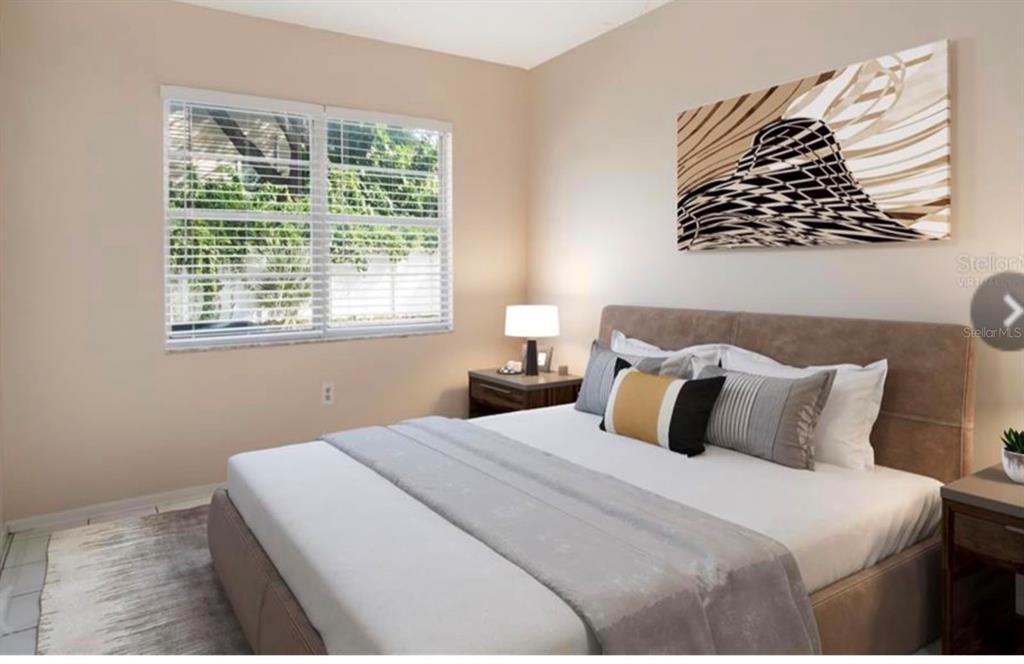 A bedroom features a bed with neutral bedding, a wall-mounted abstract painting, and a window — 6010 AMBERLY AVENUE UNIT F, ORLANDO, FL