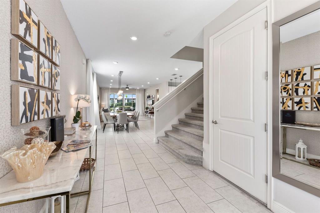An entryway with tile flooring leads to a staircase and an open-concept dining area — 353 SOUTHFIELD STREET, KISSIMMEE, FL