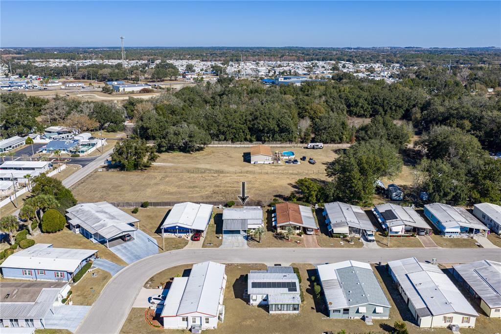 An aerial view shows a residential street lined with manufactured homes and a large grassy lot — 35025 MCCULLOUGHS LEAP, ZEPHYRHILLS, FL