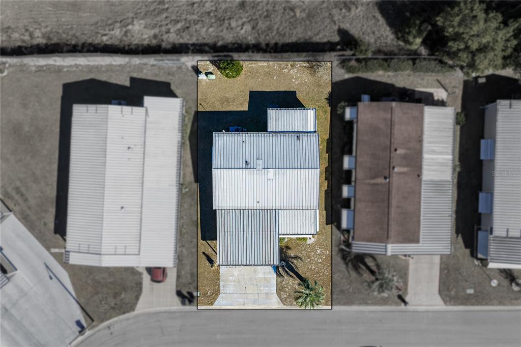 An aerial view shows a single-story house with a metal roof and a concrete driveway — 35025 MCCULLOUGHS LEAP, ZEPHYRHILLS, FL