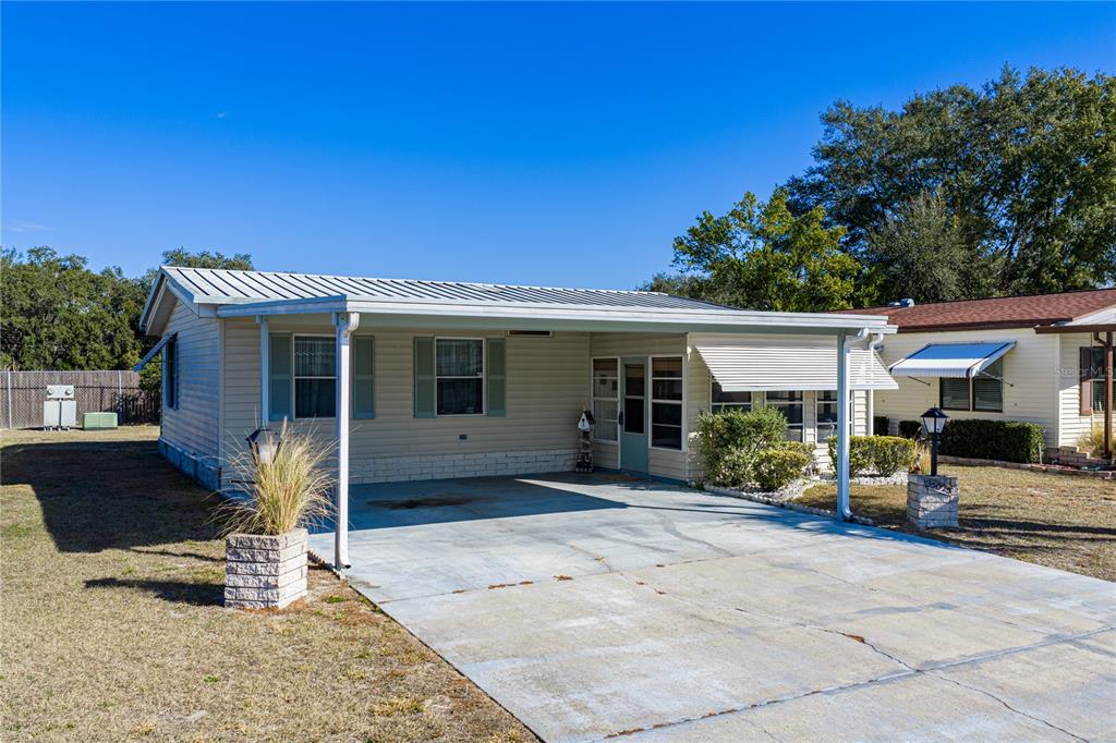 A single-story manufactured home with a metal roof, carport, and concrete driveway — 35025 MCCULLOUGHS LEAP, ZEPHYRHILLS, FL