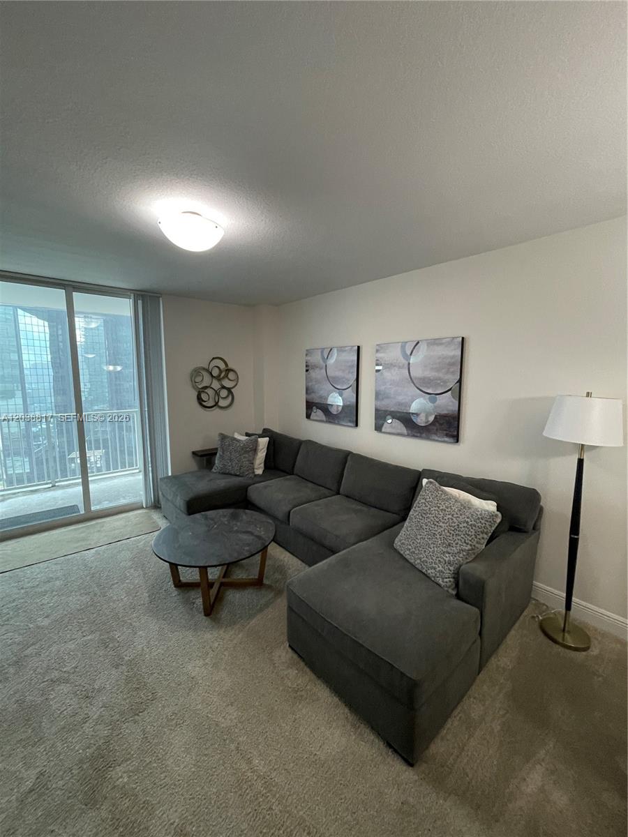 A living room features a gray sectional sofa, a round coffee table, and wall art — 1250 S Miami Ave # 1410, Miami FL 33130, MIAMI, FL