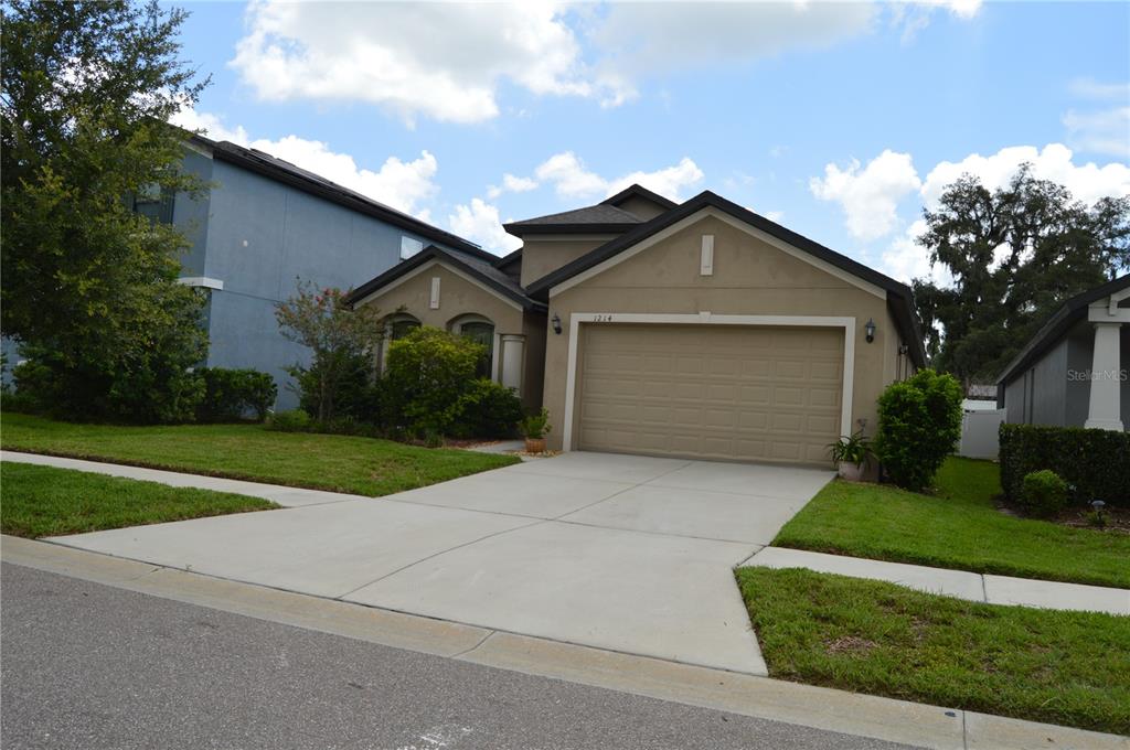 An aerial view of a tan single-story house with a two-car garage and driveway — 1214 FLORABLU DRIVE, SEFFNER, FL