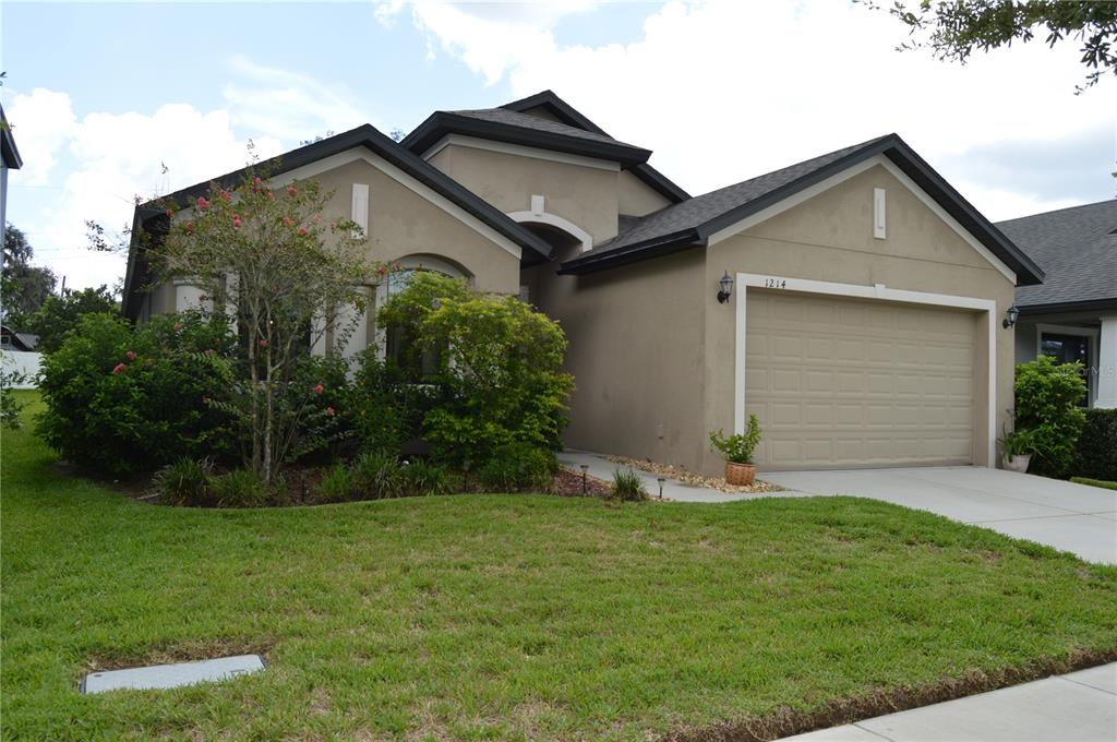 A concrete walkway leads to a dark front door under a covered entryway — 1214 FLORABLU DRIVE, SEFFNER, FL