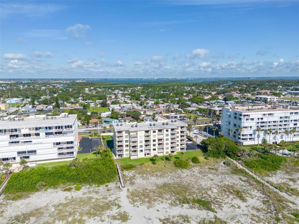 An aerial view shows three multi-story apartment buildings situated along a sandy beach — 299 N ATLANTIC AVENUE UNIT 602, COCOA BEACH, FL