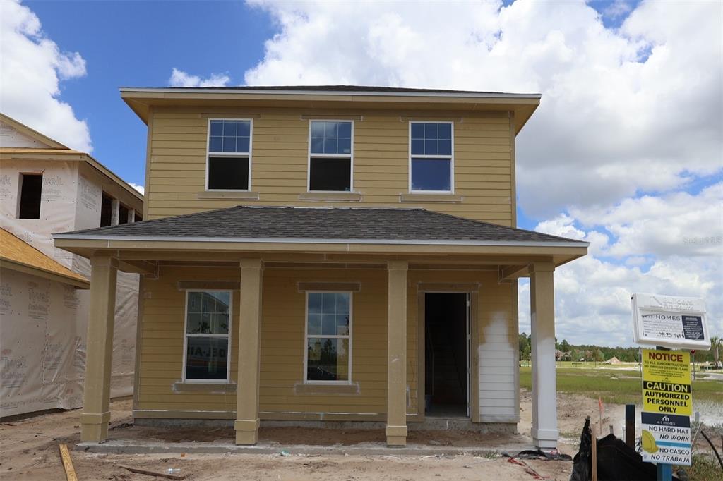 A two-story house under construction features tan siding, a covered front porch, and white-trimmed windows — 6721 RUCKSACK ROAD, ST CLOUD, FL