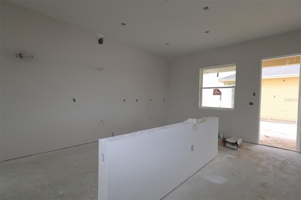 An unfinished room features drywall, a central island, recessed lighting, and a doorway to outside — 6721 RUCKSACK ROAD, ST CLOUD, FL